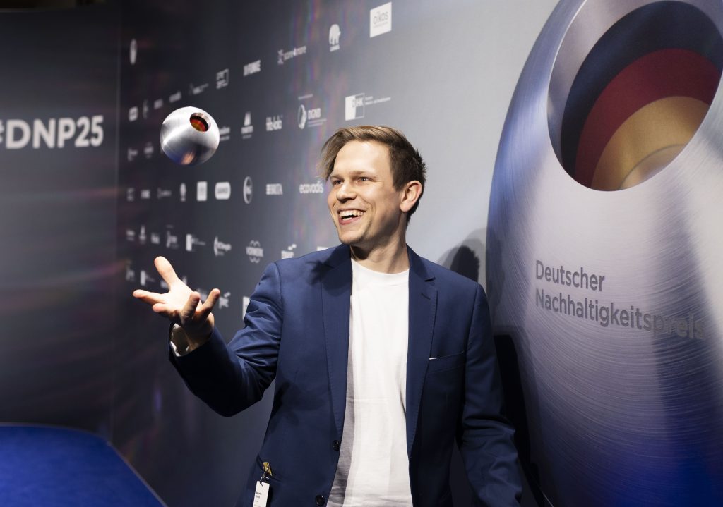 Benjamin Förtsch erhält den Deutschen Nachhaltigkeitspreis für das Hotel Luise und wirft den Preis in die Luft. 